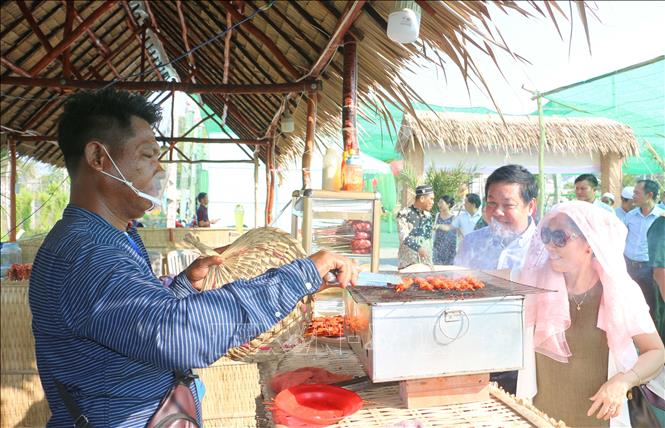 Du khách thích thú khi được trải nghiệm và thưởng thức những món đặc sản riêng có của vùng biên giới An Giang tại phiên chợ quê “Làng Chăm Đa Phước” vào những ngày cuối tuần. Ảnh: Công Mạo-TTXVN