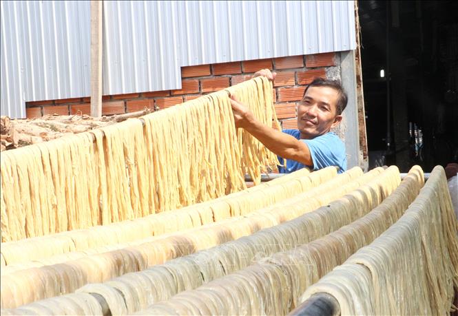 Người thợ phơi cọng tàu hũ ky lên giàn. Ảnh: Lê Thúy Hằng - TTXVN