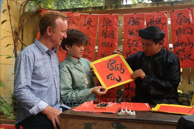 Foreign tourists are interested in calligraphy. VNA Photo: Tường Vi
