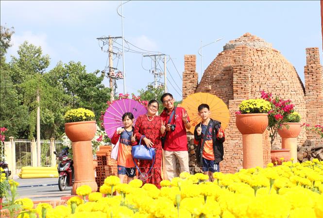 Người dân phấn khởi đi chụp ảnh trên con đường gốm và hoa xuân Giáp Thìn năm 2024 tại thành phố Vĩnh Long, tỉnh Vĩnh Long. Ảnh: Lê Thúy Hằng - TTXVN