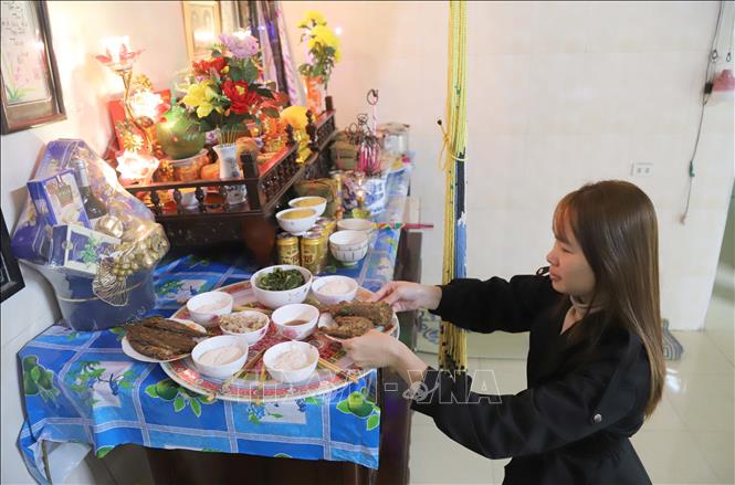 Bày biện vật phẩm cá biển kho lên mâm cúng gia tiên dịp Tết. Ảnh: Xuân Tiến - TTXVN 