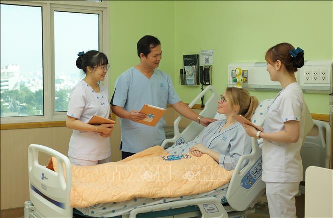 Nhân viên y tế Bệnh viện Đại học Y dược Thành phố Hồ Chí Minh sử dụng máy tính bảng cập nhật và chia sẻ thông tin với người bệnh. Ảnh: TTXVN phát