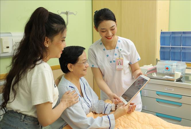  Nhân viên y tế Bệnh viện Đại học Y dược Thành phố Hồ Chí Minh sử dụng máy tính bảng cập nhật và chia sẻ thông tin với người bệnh. Ảnh: TTXVN phát