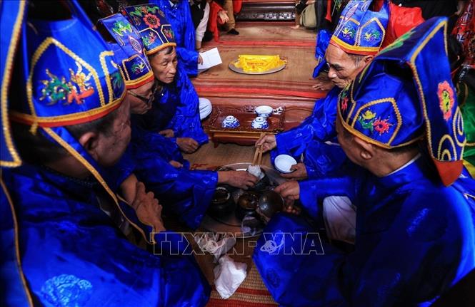 Các thành viên Ban giám khảo xới bốn bát để dâng lên Thành hoàng làng. Họ sau đó nhìn bằng mắt và dùng tay bấm thử vài hạt cơm để chấm điểm. Nồi cơm nào trắng, dẻo, thơm ngon nhất sẽ giành chiến thắng. Ảnh: Tuấn Anh - TTXVN