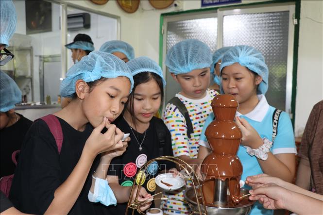 Young tourists enjoy chocolates produced by the Xuan Ron company. VNA Photo: Minh Hưng 