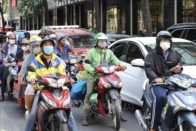 Người dân mặc trang phục “che chắn” kỹ càng cơ thể khi lưu thông trên đường. Ảnh: Hồng Giang - TTXVN