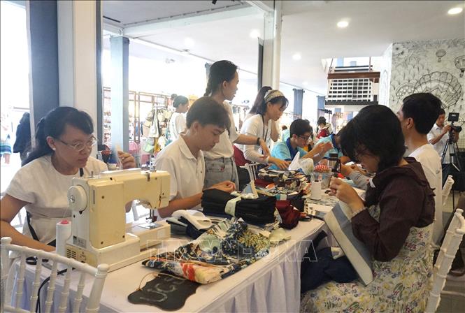 Các bạn trẻ tham gia các hoạt động tái chế, tái sử dụng quần áo ở khu vực Trạm tái chế. Ảnh: Anh Tuấn - TTXVN 