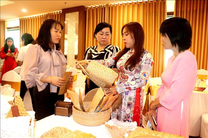 Chị Quang Chân Chân (thứ 2 từ phải qua), Chủ tịch HĐQT Công ty Cổ phần Ecoka, huyện Long Mỹ, tỉnh Hậu Giang, giới thiệu sản phẩm thủ công mỹ nghệ, thời trang được làm từ lục bình, sợi bông gòn được lấy từ địa phương. Ảnh: Thu Hiền - TTXVN
