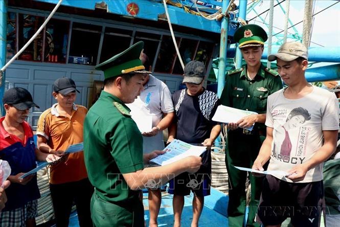 Cán bộ Đồn Biên phòng Sông Đốc (Cà Mau) phát tờ rơi tuyên truyền chống khai thác IUU cho ngư dân khu vực biên giới biển. Ảnh: Kim Há-TTXVN
