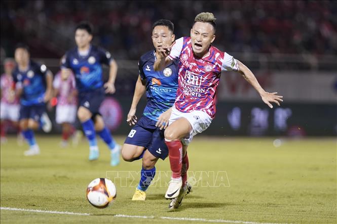  Pha tranh bóng giữa các cầu thủ câu lạc bộ Thành phố Hồ Chí Minh (áo đỏ) với Merry Land Quy Nhơn – Bình Định (áo xanh). Ảnh: Thanh Vũ - TTXVN 
