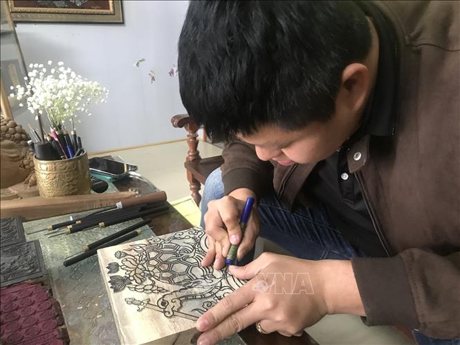 Anh Nguyễn Công Đạt làng Thanh Liễu khắc bản gỗ với tích rùa thần nhận gươm báu ở Hồ Hoàn Kiếm. Ảnh: Tiến Vĩnh - TTXVN

