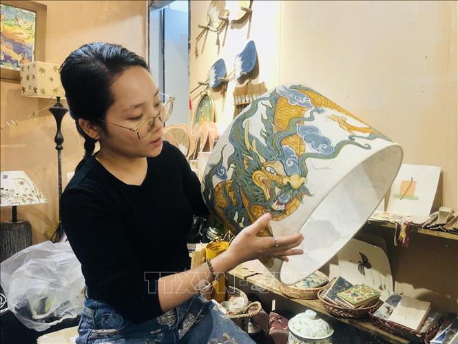 Đoàn Thái Cúc Hương với chiếc chao đèn hình con rồng được làm từ giấy truyền thống. Ảnh: Phương Lan - TTXVN