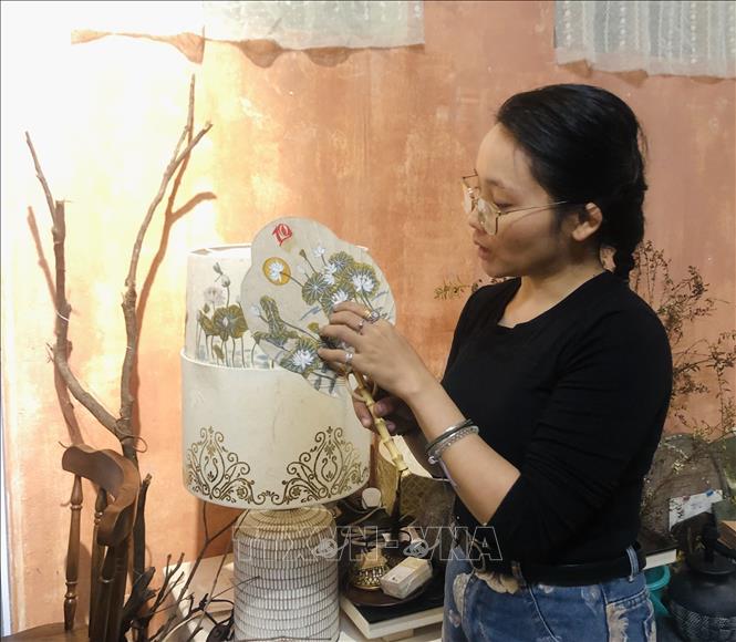 Đoàn Thái Cúc Hương giới thiệu chiếc quạt cầm tay được làm từ giấy dó. Ảnh: Phương Lan - TTXVN
