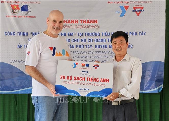 Các tình nguyện viên tổ chức YMCA of Greater Houston (Hoa Kỳ) trao tặng 70 bộ sách tiếng Anh cho Trường Tiểu học Tân Phú Tây. Ảnh: Chương Đài - TTXVN