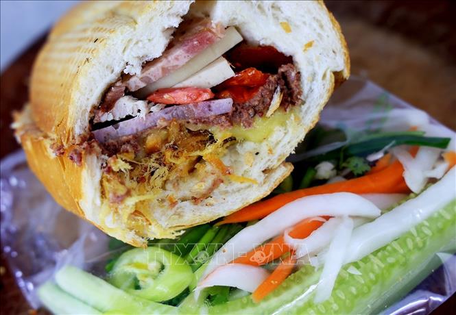 Banh mi Sai Gon (Sai Gon sandwich) actually uses a crisp-crusted short baguette filled with roasted pork meat, pork ham, pâté, pickled carrots and other vegetables, cucumbers and chili peppers, mayonnaise and sauce. VNA Photo