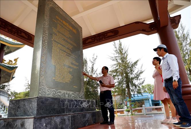 Du khách nghe giới thiệu về bia đá khắc bài văn ca ngợi công đức của Nguyễn Đình Chiểu. Ảnh: Hồng Đạt - TTXVN
