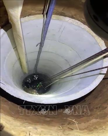 Lực lượng cứu hộ dùng dây cáp đưa thi thể anh Hiệp dưới giếng sâu lên bờ. Ảnh: TTXVN phát
