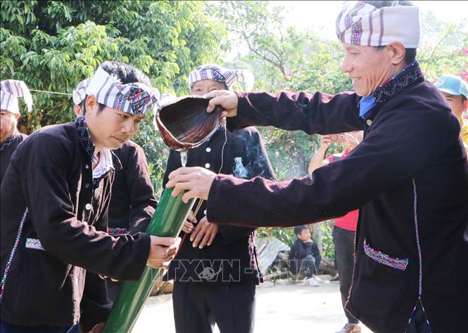 Chủ nhà trao nước mưa vào ống tre cho đoàn lễ để ra về. Ảnh: Nguyễn Oanh-TTXVN