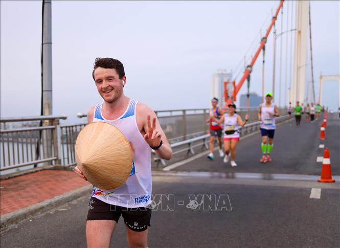 Một vận động viên quốc tế thích thú ôm chiếc nón lá Việt Nam cùng tham gia đường chạy marathon tại cuộc thi. Ảnh: Trần Lê Lâm - TTXVN 