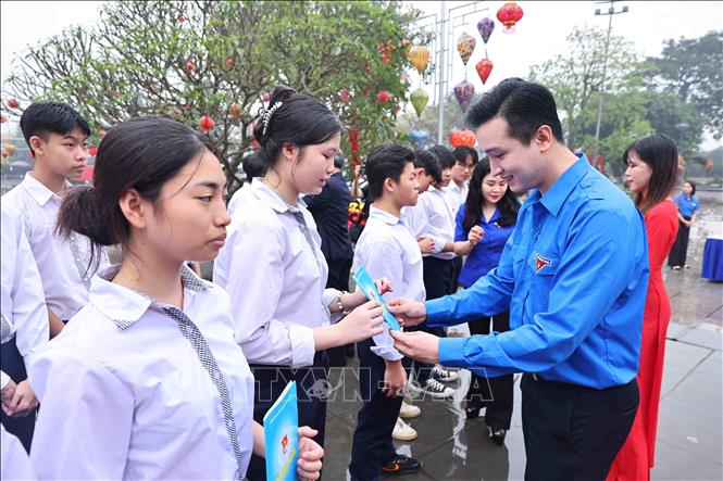 Phó Bí thư Thành đoàn Hà Nội Đào Đức Việt trao Sổ kết nạp đoàn viên mới cho học sinh. Ảnh: Minh Đức – TTXVN