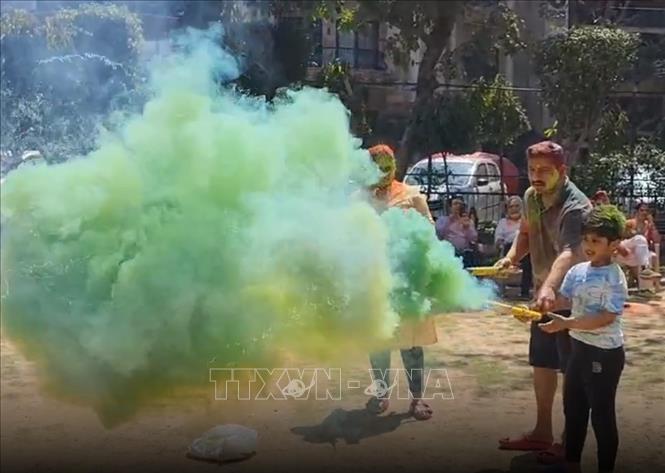 Một người bố hướng dẫn con trai nhỏ đốt pháo màu trong dịp lễ hội sắc màu Holi. Ảnh: Ngọc Thúy - P/v TTXVN tại Ấn Độ