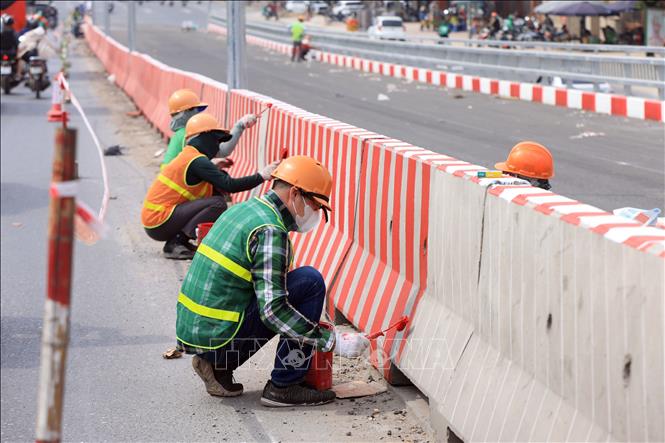 Công nhân đang gấp rút sơn hoàn thiện kẻ vạch trên các giải phân cách cứng. Ảnh: Tuấn Anh - TTXVN