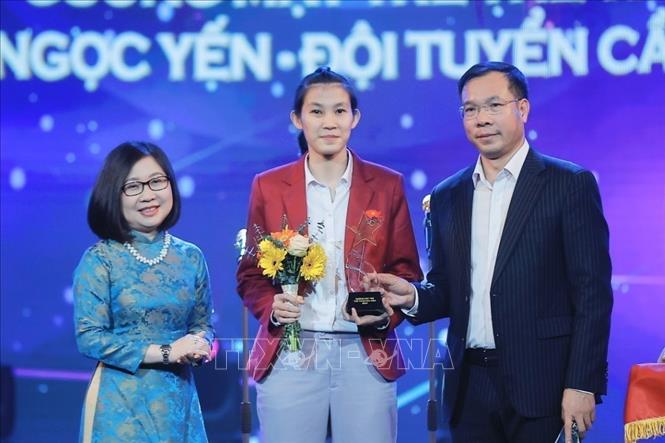 Phó Tổng giám đốc TTXVN Đoàn Thị Tuyết Nhung và HLV trưởng Đội tuyển Bắn súng Quân đội Hoàng Xuân Vinh trao giải Thể thao, hạng mục “Gương mặt trẻ thể thao của năm” cho tuyển thủ cầu mây quốc gia Trần Thị Ngọc Yến. Ảnh: Minh Quyết - TTXVN
