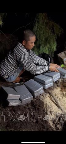 Đối tượng Nguyễn Thanh Tuấn tại nơi cất dấu 21 gói còn lại nghi làm ma túy. Ảnh: TTXVN phát 