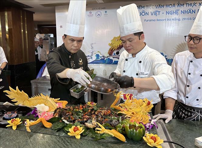 Master Chef Lê Văn Khánh (bên trái) là Tổng bếp trưởng Trung tâm Hội nghị Quốc gia đang trình diễn chế biến món ăn “Kình Ngư Hóa Long”. Ảnh: Trần Lê Lâm - TTXVN 