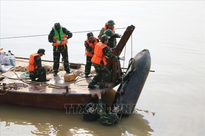 Lực lượng chức năng tiến hành trục vớt quả bom chưa nổ dưới sông Hồng, cách chân cầu Long Biên về phía thượng lưu khoảng 600m. Quả bom dài 1,6m, có đường kính khoảng 35cm, nằm sâu 2m. Ảnh: Thành Đạt - TTXVN