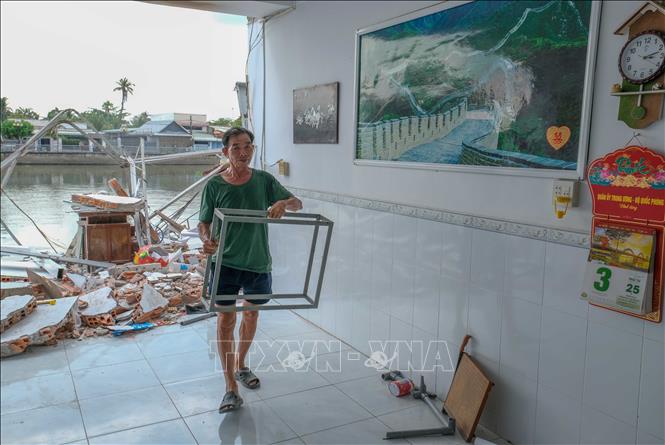 Ông Nguyễn Văn Danh chủ nhà số 54, đường Lê Thị Hồng Gấm, khu vực 2, phường Trà An, quận Bình Thủy thu dọn đồ đạc còn sót lại sau vụ sạt lở. Ảnh: Thanh Liêm - TTXVN