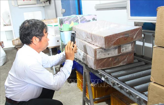 Cán bộ trong đoàn kiểm tra liên ngành về an toàn thực phẩm tỉnh Khánh Hòa quét mã QR tra cứu nguồn gốc xuất xứ của hàng đông lạnh nhập khẩu ở Cơ sở Đường 2/4, phường Vĩnh Hải, thành phố Nha Trang, sáng 8/4. Ảnh: Phan Sáu -TTXVN