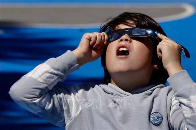 Em nhỏ thích thú quan sát hiện tượng nhật thực toàn phần tại Los Angeles, California, Mỹ ngày 8/4/2024. Ảnh: THX/TTXVN
