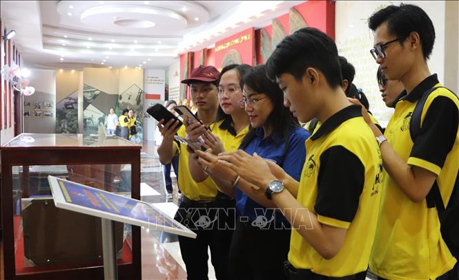Khách tham quan quét mã QR tra thông tin của Khu di tích Chiến thắng Chương Thiện. Ảnh: Hồng Thái - TTXVN