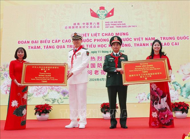 Bộ trưởng Quốc phòng Phan Văn Giang và Bộ trưởng Quốc phòng Trung Quốc Đổng Quân tặng quà lưu niệm cho Trường Tiểu học Kim Đồng (thành phố Lào Cai). Ảnh: Trọng Đức - TTXVN