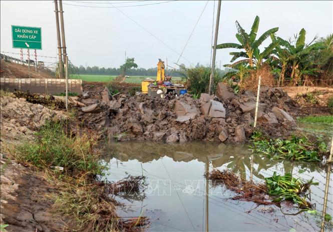 Một xe cuốc được điều động đến để múc đất đắp kín đoạn bờ bao bị vỡ, ngăn chặn nước tràn vào đồng ruộng, đồng thời, lắp đặt cống phục vụ việc tưới tiêu nước. Ảnh: Nhựt An - TTXVN