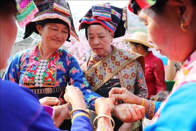 Nghi thức buộc chỉ cầu may. Ảnh: Trung Kiên - TTXVN