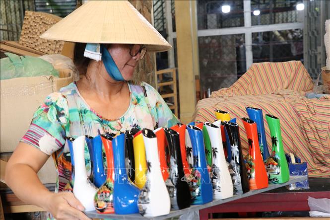 A Tuong Binh Hiep villager carries vases painted in lacquer. VNA Photo: Dương Chí Tưởng