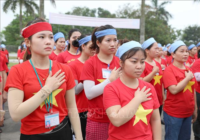 Công nhân Công ty TNHH Wooin Vina (Cụm công nghiệp Tháp - Hồng - Kỷ, huyện Diễn Châu) mặc áo đỏ sao vàng, nghiêm trang chào cờ. Ảnh: Xuân Tiến - TTXVN 