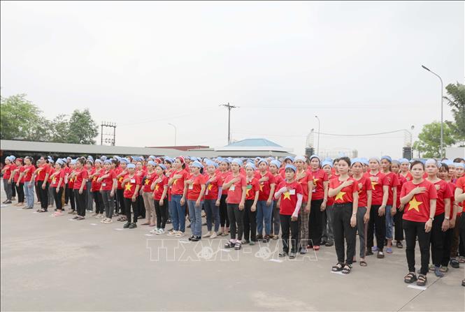 Công nhân Công ty TNHH Wooin Vina (Cụm công nghiệp Tháp - Hồng - Kỷ, huyện Diễn Châu) mặc áo đỏ sao vàng, nghiêm trang chào cờ. Ảnh: Xuân Tiến - TTXVN