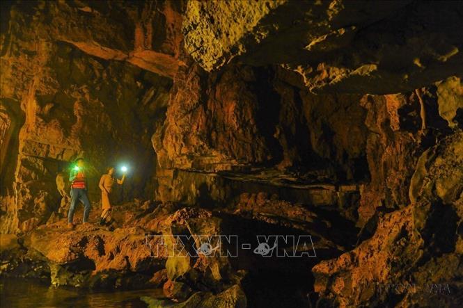 Du khách khám phá hang động trong Quần thể danh thắng Tràng An. Ảnh: Minh Đức - TTXVN