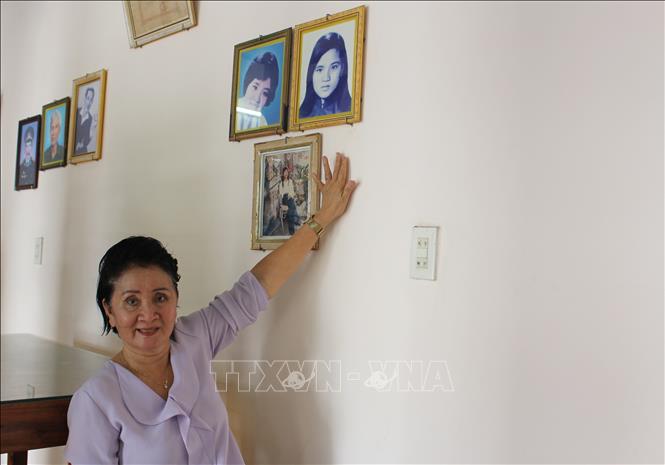 Bà Nguyễn Thị Ngọc Bích kể chuyện về sự kiện gia đình bà may 2 lá cờ giải phóng trước những năm 1975 và hình ảnh của chị gái - liệt sĩ Nguyễn Thị Ngọc Oanh. Ảnh: Phan Sáu - TTXVN
