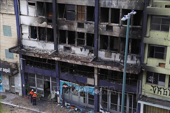 Lính cứu hỏa làm nhiệm vụ tại hiện trường vụ cháy tòa khách sạn cũ ở Porto Alegre, Brazil, ngày 26/4/2024. Ảnh: AFP/TTXVN