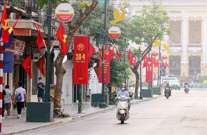 Trang Tien street is decorated with national flags and red panels on the National Reunification Day. VNA Photo: Phạm Kiên