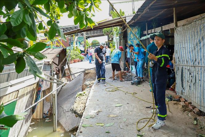 Lực lượng chức năng hỗ trợ người dân tháo dỡ, di dời tài sản trong vụ sạt lở bờ sông Thốt Nốt xảy ra ngày 30/4, làm 3 căn nhà bị đổ sập xuống sông. Ảnh: TTXVN phát