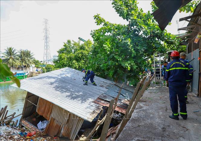 Lực lượng chức năng hỗ trợ người dân tháo dỡ, di dời tài sản trong vụ sạt lở bờ sông Thốt Nốt xảy ra ngày 30/4, làm 3 căn nhà bị đổ xuống sông. Ảnh: TTXVN phát