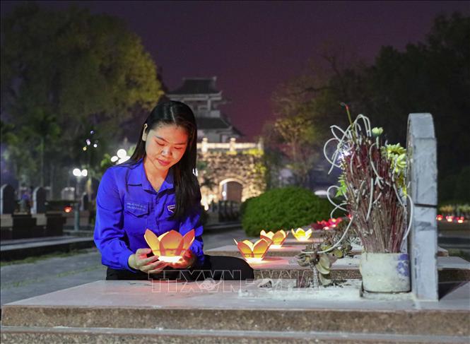 Đoàn viên thanh niên thắp những ngọn nến lung linh lên các phần mộ liệt sĩ. Ảnh: Xuân Tư - TTXVN