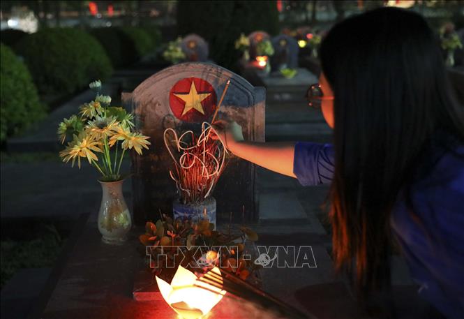 Đoàn viên thanh niên thắp hương lên các phần mộ liệt sĩ. Ảnh: Xuân Tư - TTXVN