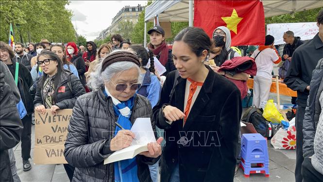 Bà Trần Tố Nga ký sách cho những người ủng hộ mình. Ảnh: Thu Hà - PV TTXVN tại Pháp
