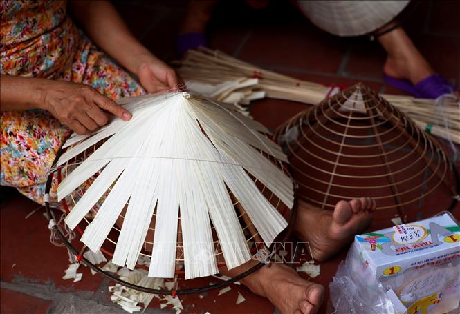 First, artisans place a layer of dried palm leaves on the conical frame, overlaying  with another layer of areca leaves and bamboo, then sew them together. This is the hardest part of the non la making process because the leaves are super thin and can easily crack. VNA Photo: Hồng Đạt